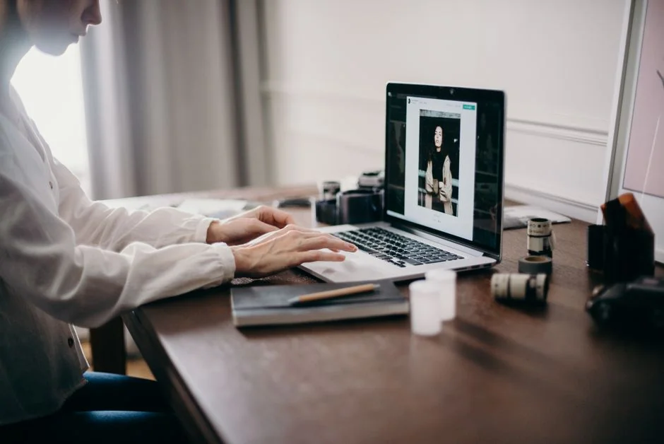 Hands typing on a laptop showing an e-commerce website in a modern office setting.